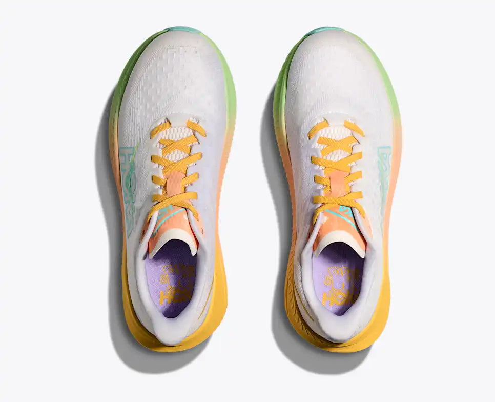 White running shoe with yellow and green sole on a white background
